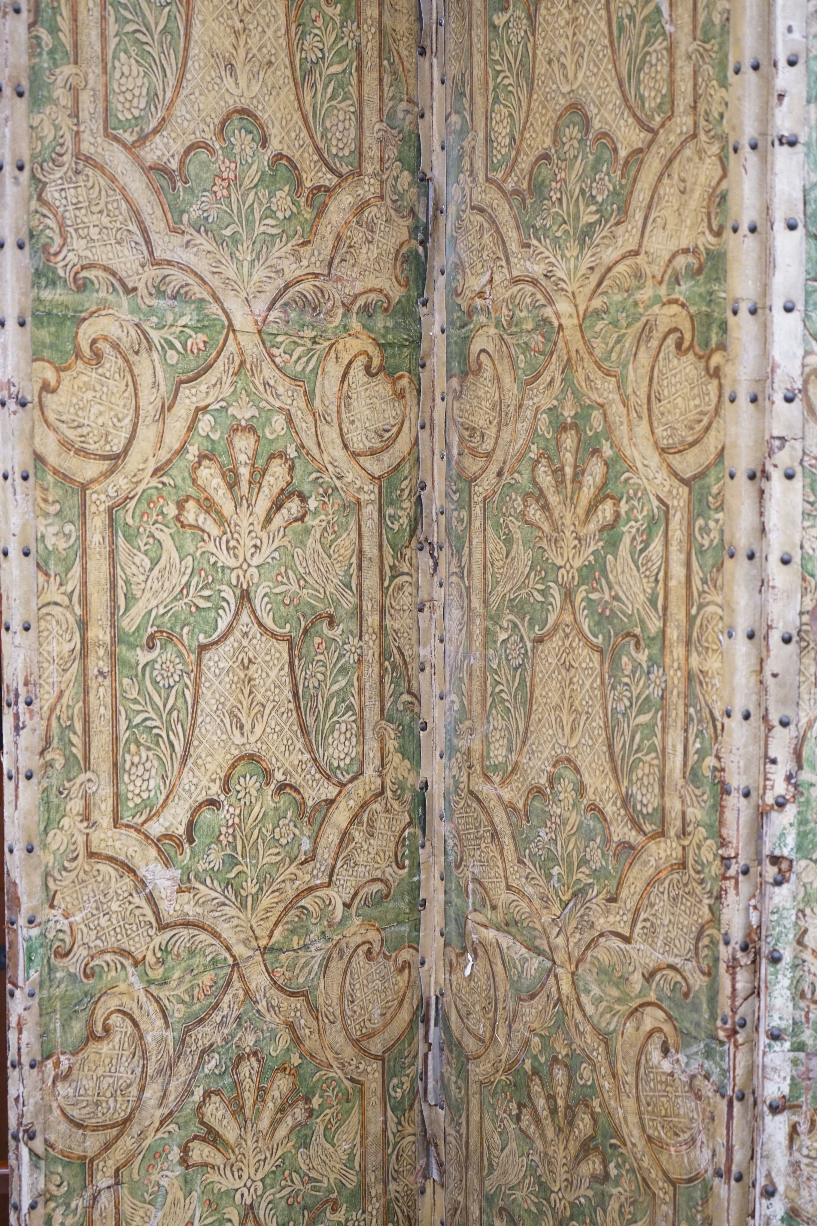 A Spanish painted leather three fold dressing screen, each panel width 60cm, height 237cm